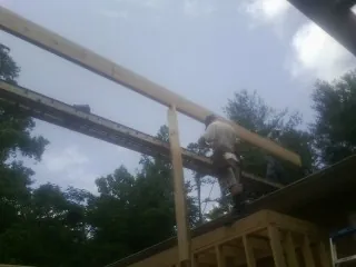 Carpenter setting a ridge beam over a new addition frame — Ice Dam Removal by Roofing Brothers in Sweetser