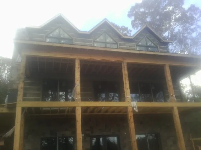 Dormers and porch framing on a large log home under construction — Roof Coating work by our crew in Sweetser