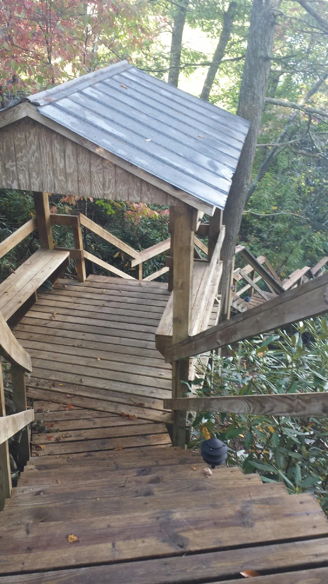 Metal roofed shelter over wooden steps on a wooded walkway — Skylight Repair & Installation work by our crew in Sweetser