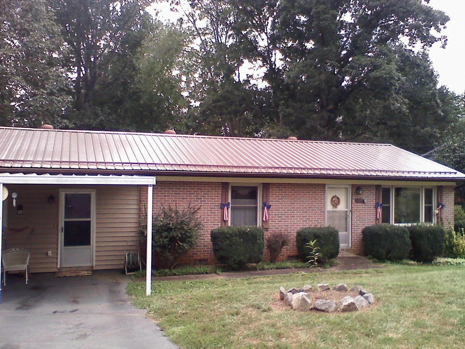 Bronze metal roof and carport on a brick ranch home — Roof Repair work by our crew in Sweetser